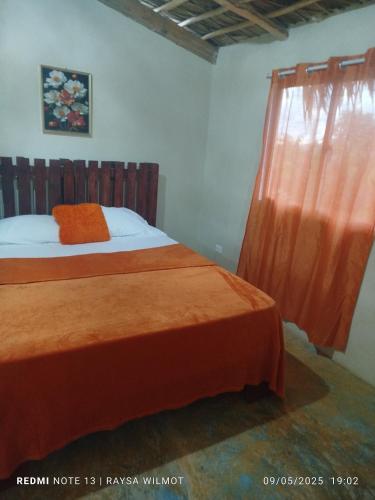 ein Schlafzimmer mit einem Bett mit einer orangefarbenen Decke und einem Fenster in der Unterkunft Parador tropical in Las Galeras