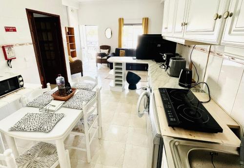 een keuken met witte kasten, een tafel en een fornuis bij Casa do Omega do Foz in Foz do Arelho