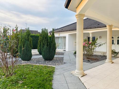 ein Haus mit einer Veranda mit Büschen und Bäumen in der Unterkunft Sweet Escape - Studio privé proche du lac du Der in Frignicourt