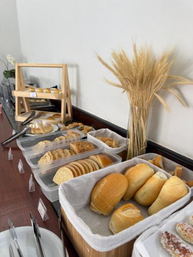 um bufê com muitos tipos diferentes de pão em bandejas em Hotel Roma em São Sebastião