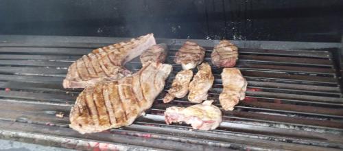 a bunch of meat cooking on a grill at Hostal prados abiertos in La Parra