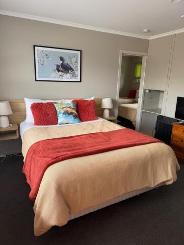 a bedroom with a large bed with red pillows at Lumsden Motel in Lumsden