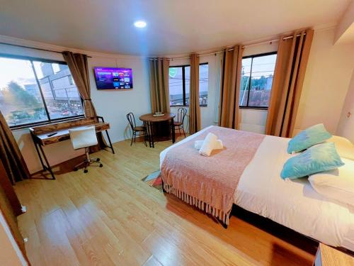 Un dormitorio con cama, escritorio y ventanas en Aloja Hotel - Ex Bilbao, en Osorno