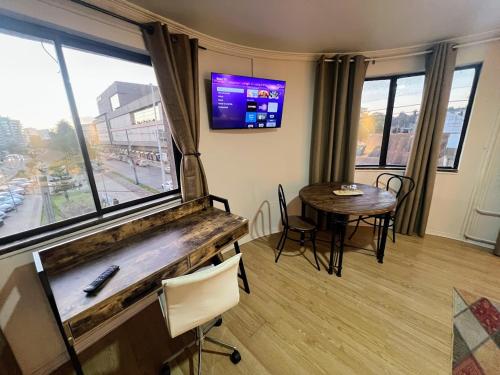 Una sala de estar con una mesa y una gran ventana. en Aloja Hotel - Ex Bilbao, en Osorno