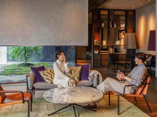 two men sitting in chairs in a living room at Pullman Tokyo Tamachi in Tokyo