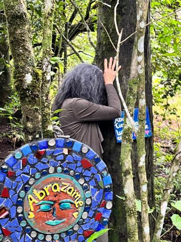 Eine Person lehnt an einem Baum mit einem Mosaikschild in der Unterkunft Apartamento ArteSAna in Monteverde Costa Rica