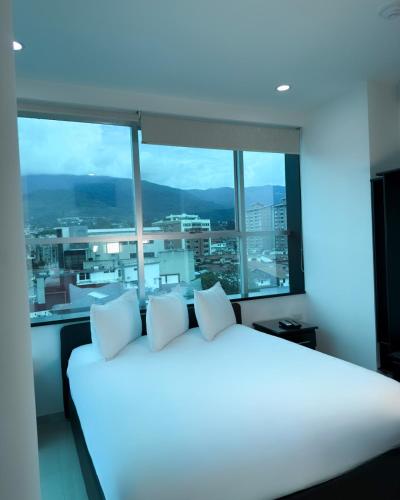 a white bed in a room with a large window at Hotel Virgen de Guadalupe in San Cristóbal