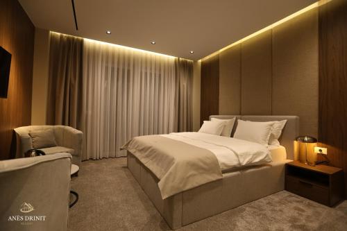 a bedroom with a large bed and a chair at Resort Anes Drinit in Peje