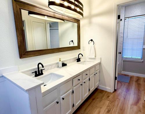 Modern and Cozy 3BR Retreat Perfect for Families or Big Group في سيدار بارك: حمام به مغسلتين ومرآة كبيرة