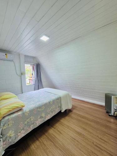 una camera da letto con un letto in una stanza bianca di Cabana Amarela Guarda do Embaú a Palhoça