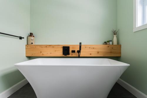 a white bath tub in a bathroom with a wooden shelf at Le 4 sur le lac, Accès au lac, Boisée, BBQ in Wentworth
