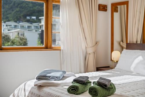 a bedroom with a bed with towels and a window at The Signal - Stylish Deco Apt with Deck and Marina View in Picton