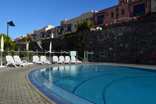 a swimming pool with lounge chairs next to a building at Gurugu Beach House in Palm-Mar