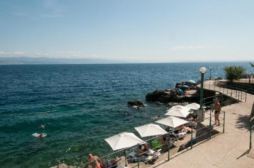 a beach with white umbrellas and people in the water at Apartment Tomic A-5 in Lovran