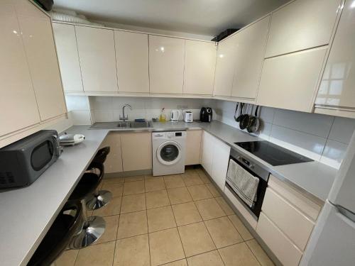 a small kitchen with white cabinets and a washing machine at Stylish Room in Central London! in London
