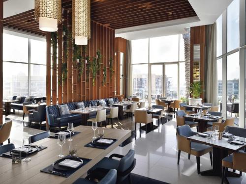 a restaurant with tables and chairs and windows at Grand Plaza Mövenpick Media City in Dubai