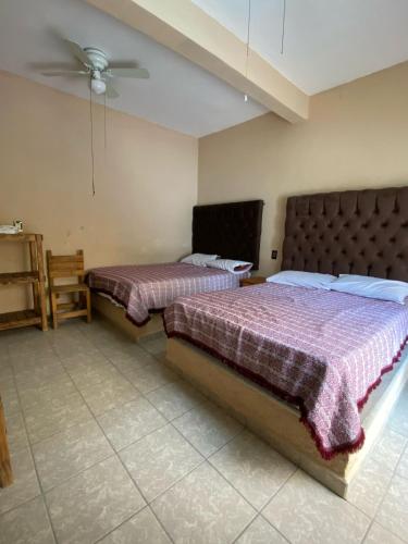 a bedroom with two beds and a ceiling fan at Casa de los Abuelos in Itzamatitlán