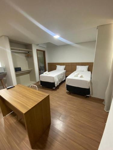 ein Hotelzimmer mit zwei Betten und einem Tisch in der Unterkunft San Diego Suítes Manhuaçu in Manhuaçu