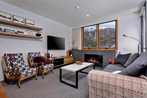 a living room with a couch and a fireplace at Alpine Gloria - Squatters 17 in Thredbo