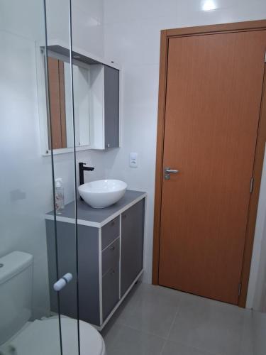 a bathroom with a sink and a toilet and a door at Apartamento moderno próximo ao centro in União da Vitória