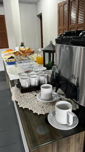 a counter with cups of coffee on plates on at Pousada maré torres in Torres