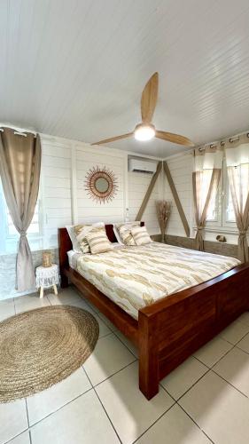 a bedroom with a large bed and a ceiling fan at MAJO LOUNGE dans un jardin tropical vue mer ,5 min de la plage Caraïbe in Saint-Pierre