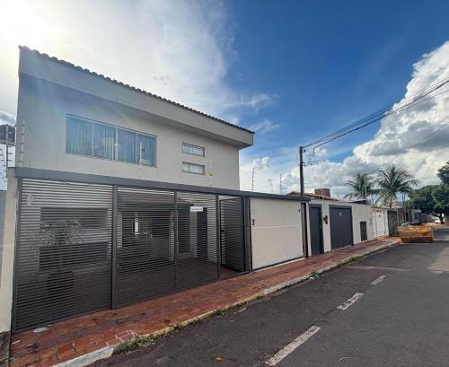 a white building with gates on the side of a street at Hotel Pousada Accordes in Campo Grande