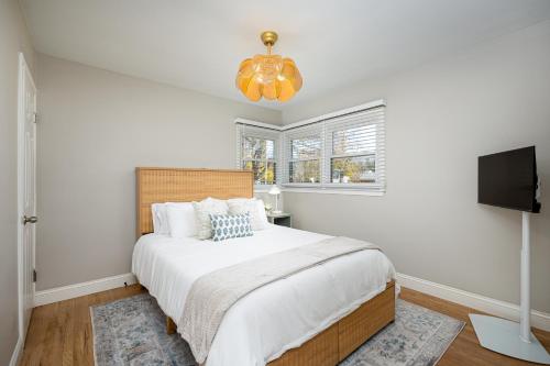 a white bedroom with a bed and a tv at Main Street Retreat Hot Tub Sleeps 8 in Plymouth