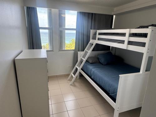 Beach front 2 bedroom & bath in Isla Verde في سان خوان: غرفة نوم مع سرير بطابقين وسلّم