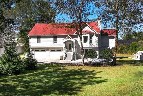 Casa blanca con techo rojo y patio en Spacious 5BR Family Retreat Near Mall of GA Sleeps 13, en Buford