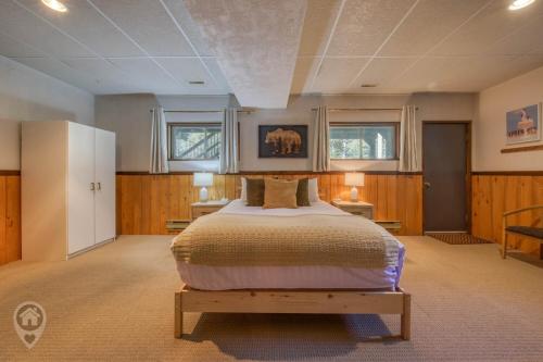 a bedroom with a bed and two tables and two windows at Pet-Friendly Original Ski Cabin by StayIn in Panorama