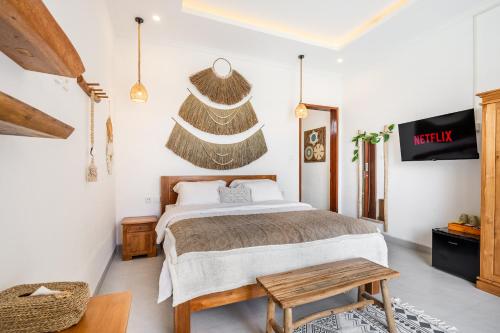 ein Schlafzimmer mit einem Bett, einem Tisch und einem Fernseher in der Unterkunft Boho Majipso Dreamy in Munggu