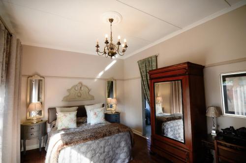 a bedroom with a bed and a chandelier at Villa Brocant Guest house in Vryburg