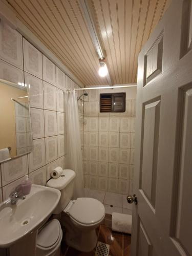 a bathroom with a white toilet and a sink at Hostal Purilackti in San Pedro de Atacama
