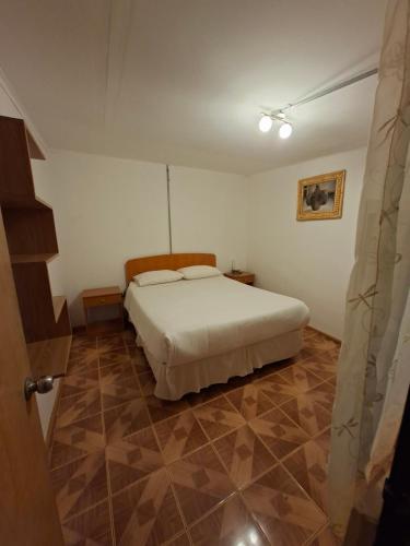 a bedroom with a white bed and a tiled floor at Hostal Purilackti in San Pedro de Atacama