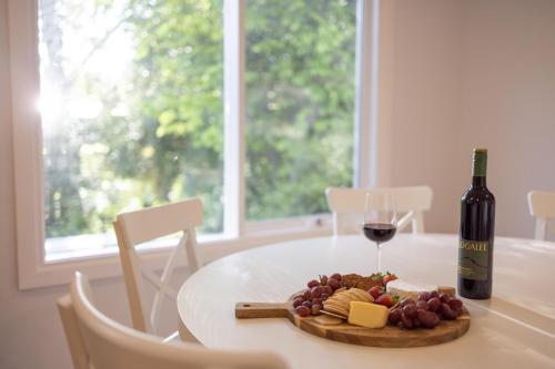 a table with a glass of wine and a plate of cheese and grapes at Donnybrook Cottages - Donnybrook in Clare