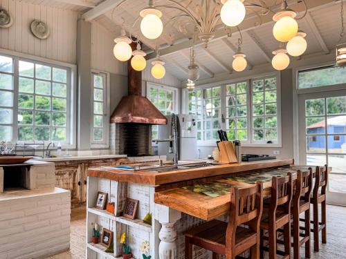 a kitchen with a large counter with chairs around it at Teresopolis casa ampla em clube com piscina in Teresópolis