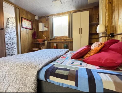 a bedroom with a large bed with red pillows at Casa de 1 quarto a cinco minutos da praia in Florianópolis