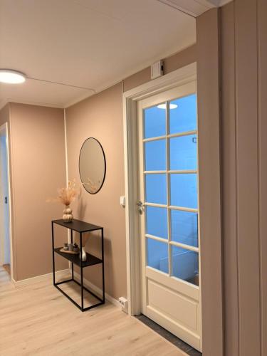 a room with a door and a mirror and a table at Kirkevegen apartment in Brumunddalen
