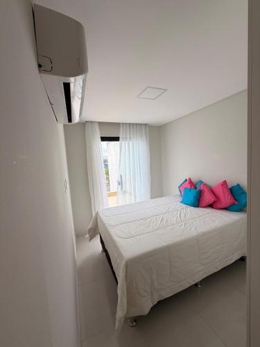 a bedroom with a bed with blue and pink pillows at Refúgio de luxo in Pedra de Guaratiba