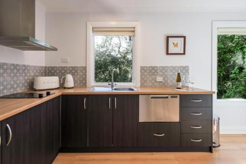 a kitchen with brown cabinets and a sink at Donnybrook Cottages - Donnybrook in Clare