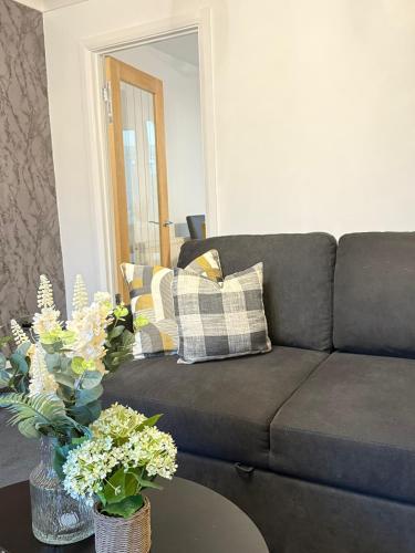 a living room with a couch and flowers on a table at Wigan Modern house - Cozy & Relaxing Stay in Bickershaw