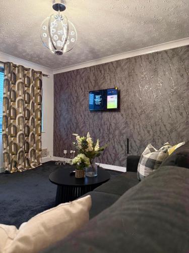 a living room with a couch and a tv on a wall at Wigan Modern house - Cozy & Relaxing Stay in Bickershaw