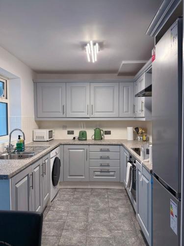 a kitchen with white cabinets and a dishwasher at Wigan Modern house - Cozy & Relaxing Stay in Bickershaw
