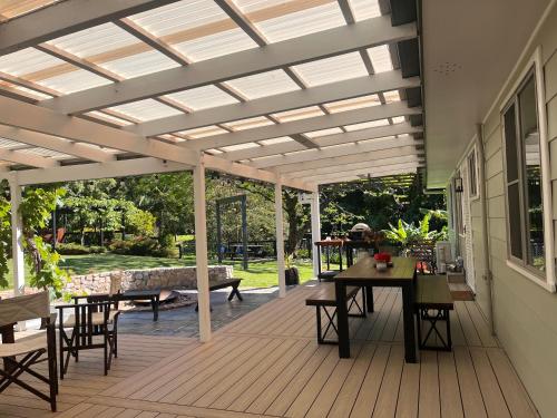 a pergola on a deck with a table and chairs at Cedarvale Cottage in Boambee