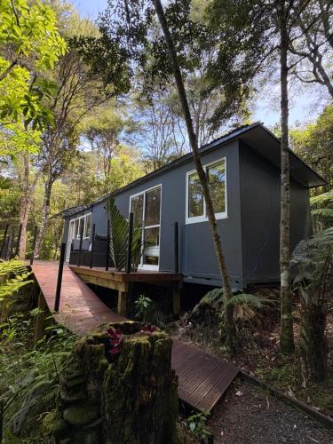 a gray tiny house in the woods at Tui Bush Chalet and Hot tub in Parakakau