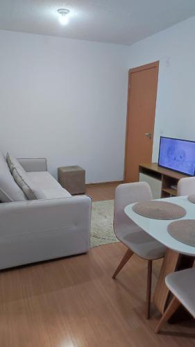 een woonkamer met een witte bank en een tafel bij Apartamento Santa Isabel in Cuiabá