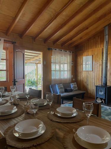 ein Esszimmer mit einem Tisch mit Tellern und Weingläsern in der Unterkunft Cabaña AlbaMarina - Pichilemu in Pichilemu