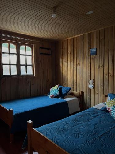 zwei Betten in einem Zimmer mit Holzwänden in der Unterkunft Cabaña AlbaMarina - Pichilemu in Pichilemu