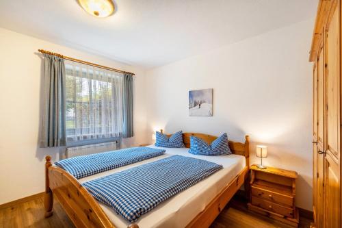 a bedroom with a bed with blue sheets and a window at Fewo Brünnstein - Zimmer 6 in Oberaudorf
